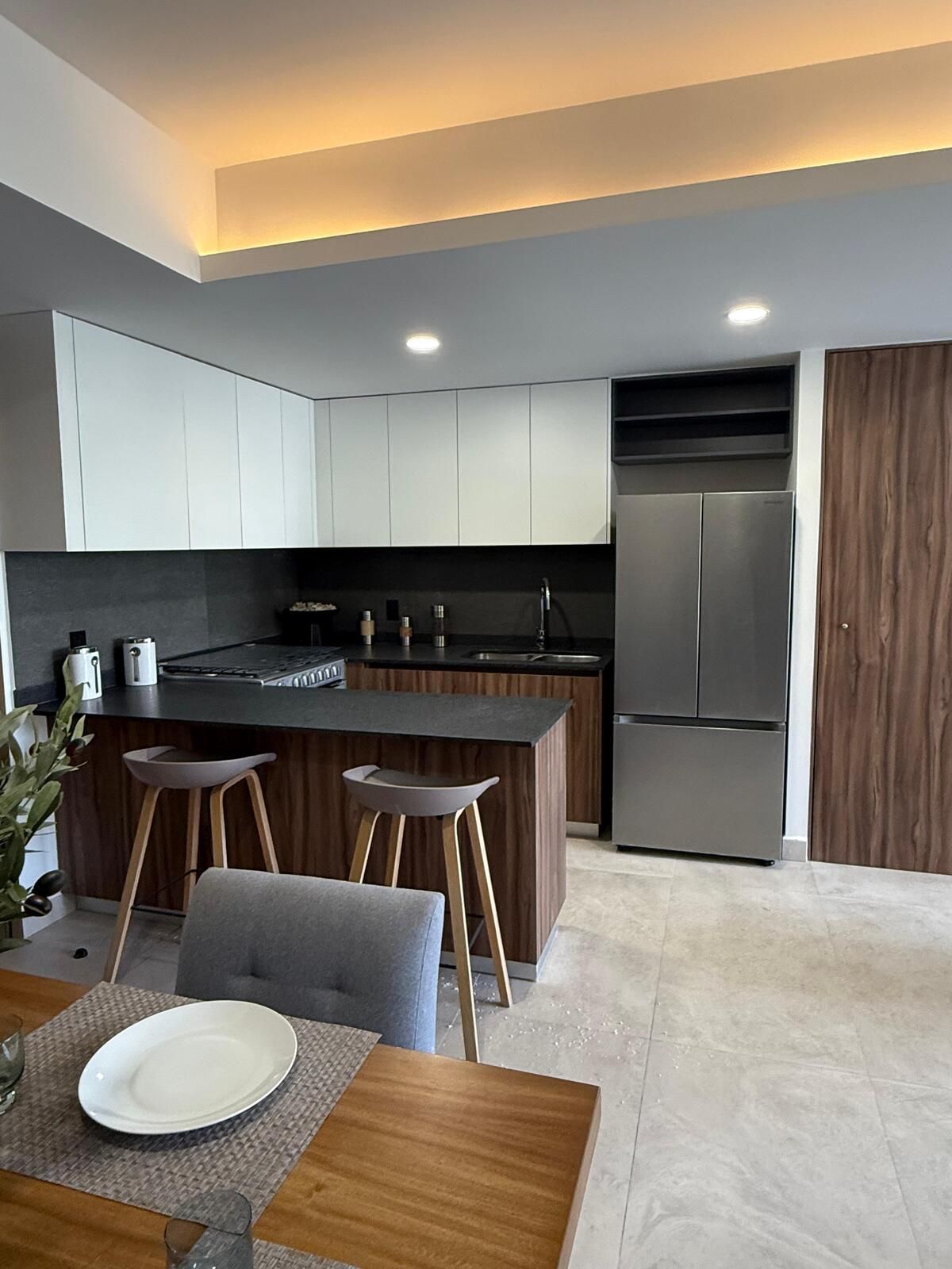 Cocina integral con cubierta negra y barra de madera